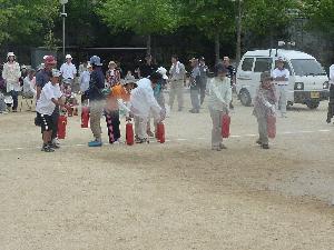 訓練用の消火器で、使い方と消し方を学ぶ画像