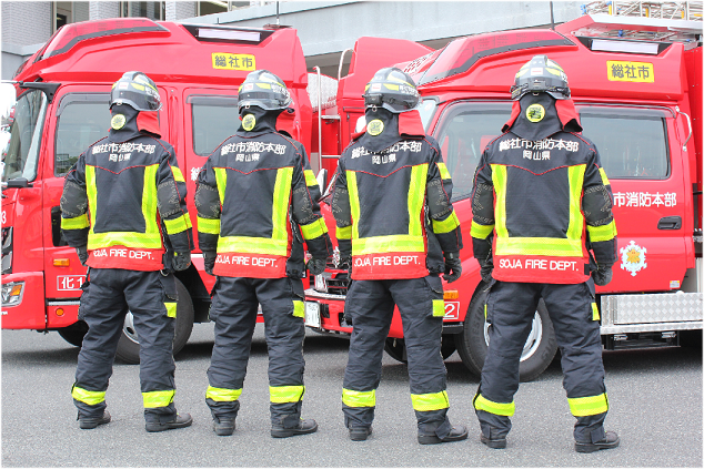 防火装備を装着し並ぶ4人の消防士の後面画像