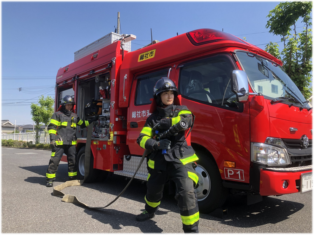 消防ポンプ自動車からホースを伸ばして放水姿勢をする画像