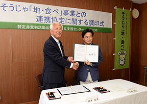 協定書を手に握手を交わす