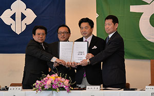 協定書を手に握手する両市の市長と議長